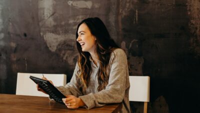 woman sitting around table holding tablet